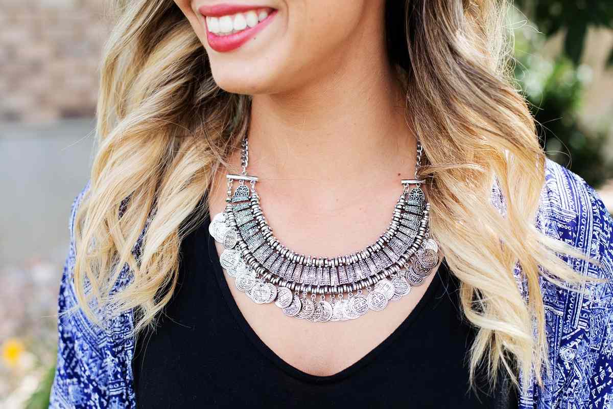 Femme souriante portant un collier argenté imposant sur un haut noir Femme souriante portant un collier argenté imposant sur un haut noir