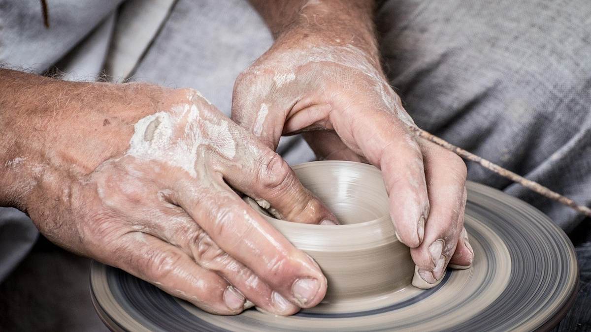 Mains couvertes de terre modelant un objet sur un tour