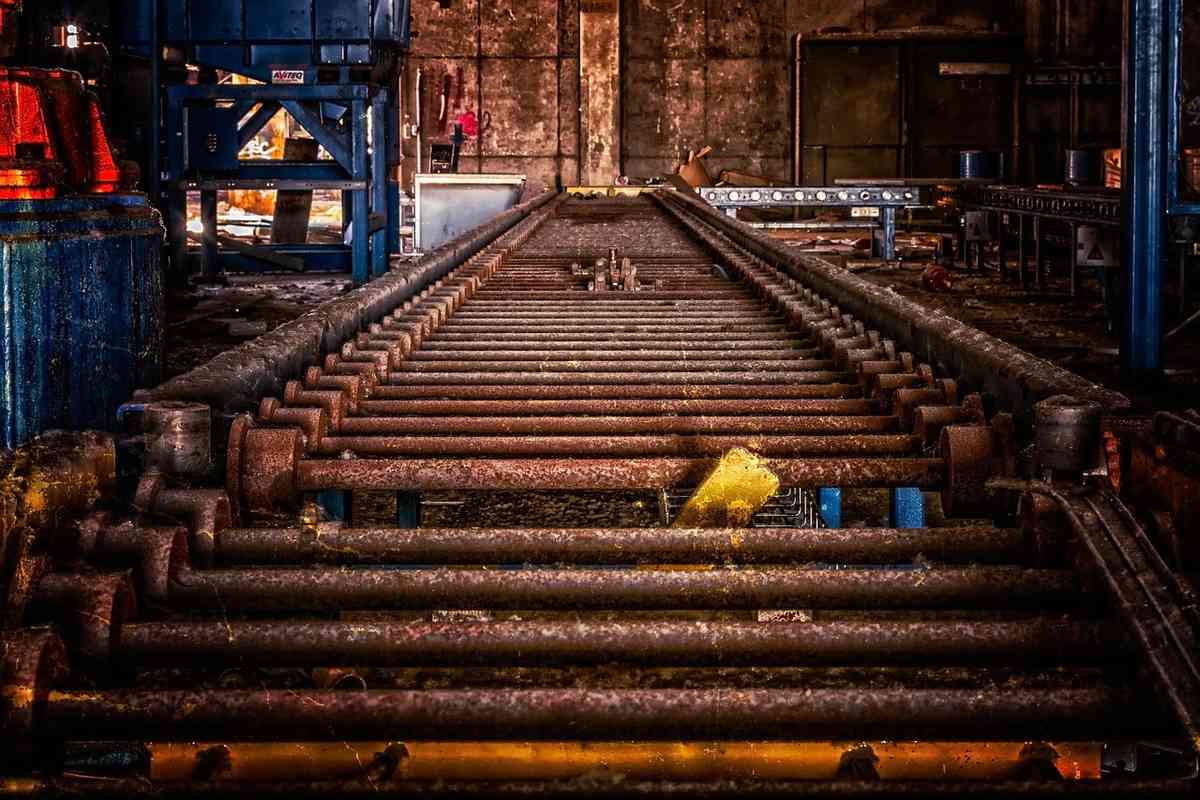 Usine abandonnée avec rails rouillés et un petit oiseau jaune posé Usine abandonnée avec rails rouillés et un petit oiseau jaune posé
