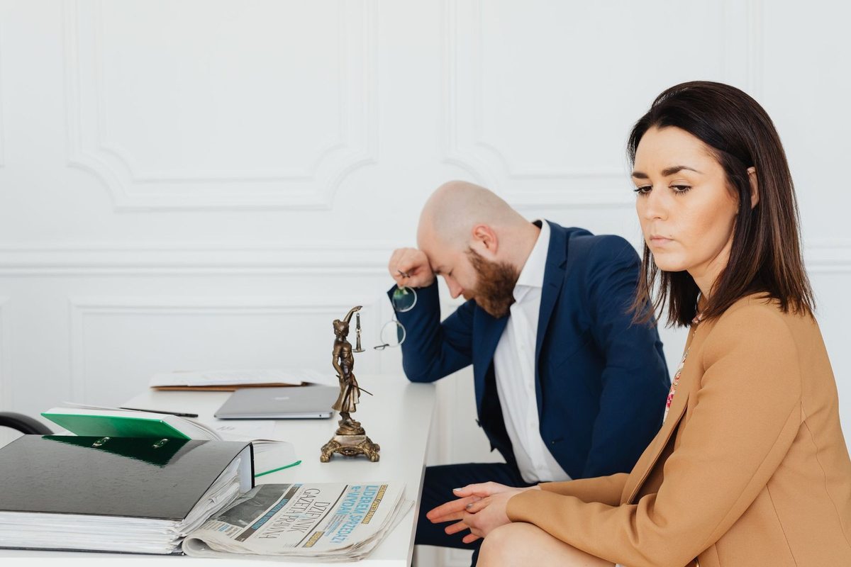 Homme et femme en réunion professionnelle, documents et statue de justice sur le bureau Homme et femme en réunion professionnelle, documents et statue de justice sur le bureau