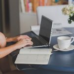 Une femme travaille à distance, écrivant sur ordinateur et prenant notes