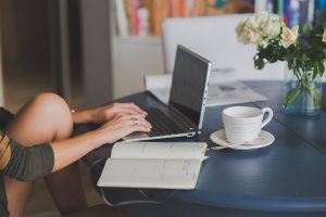 Une femme travaille à distance, écrivant sur ordinateur et prenant notes
