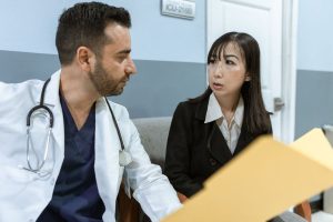 Médecin et femme en conversation dans un cabinet médical avec un dossier sur la table