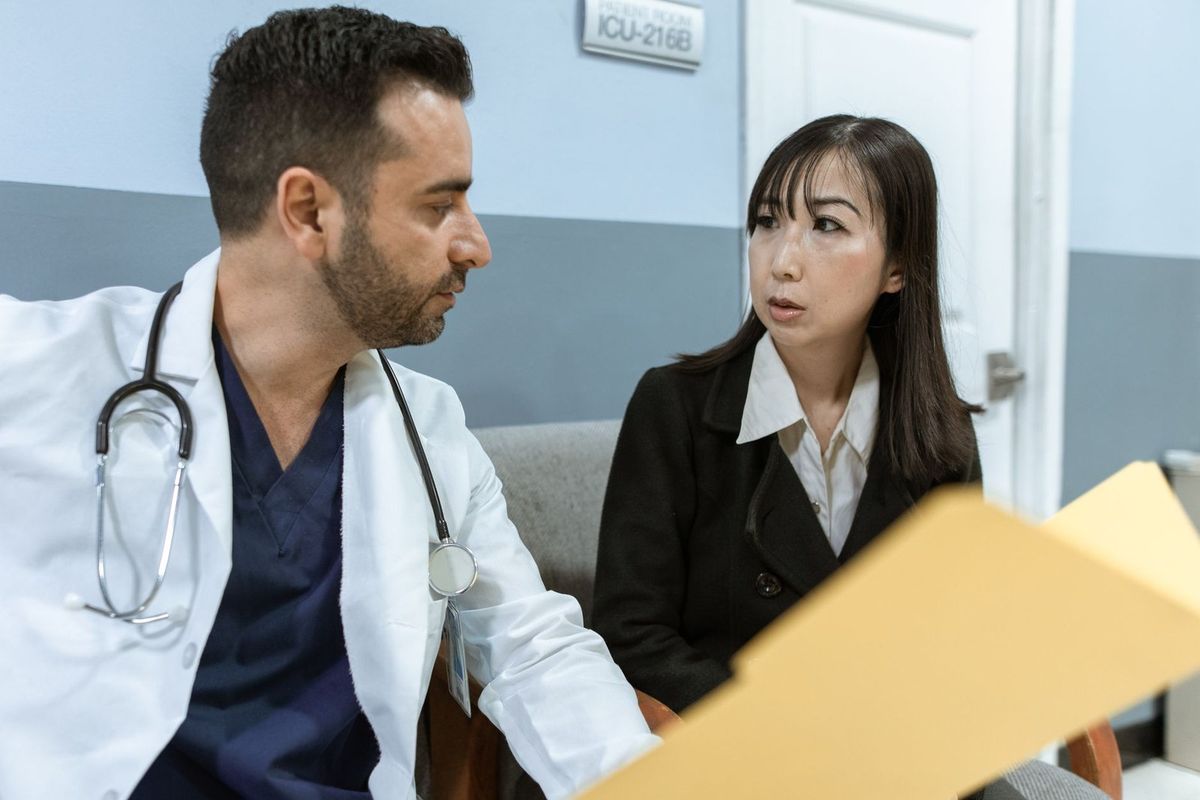 Médecin et femme en conversation dans un cabinet médical avec un dossier sur la table